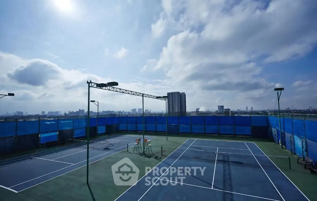 Stunning rooftop tennis court with city skyline view, perfect for sports enthusiasts.