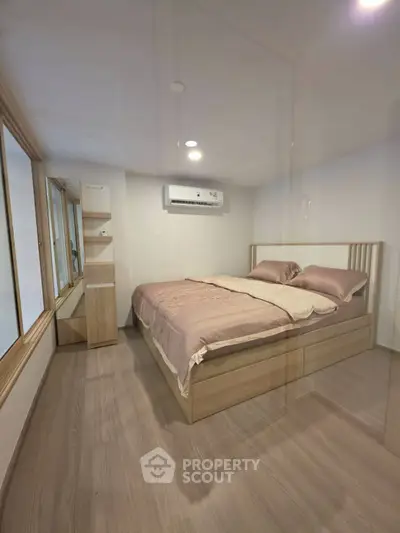 Cozy bedroom with modern wooden furniture and air conditioning, perfect for relaxation and comfort.