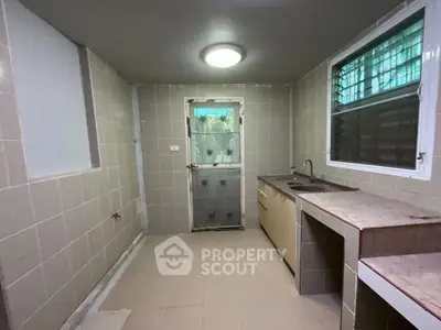 Spacious tiled kitchen with ample counter space and natural light.