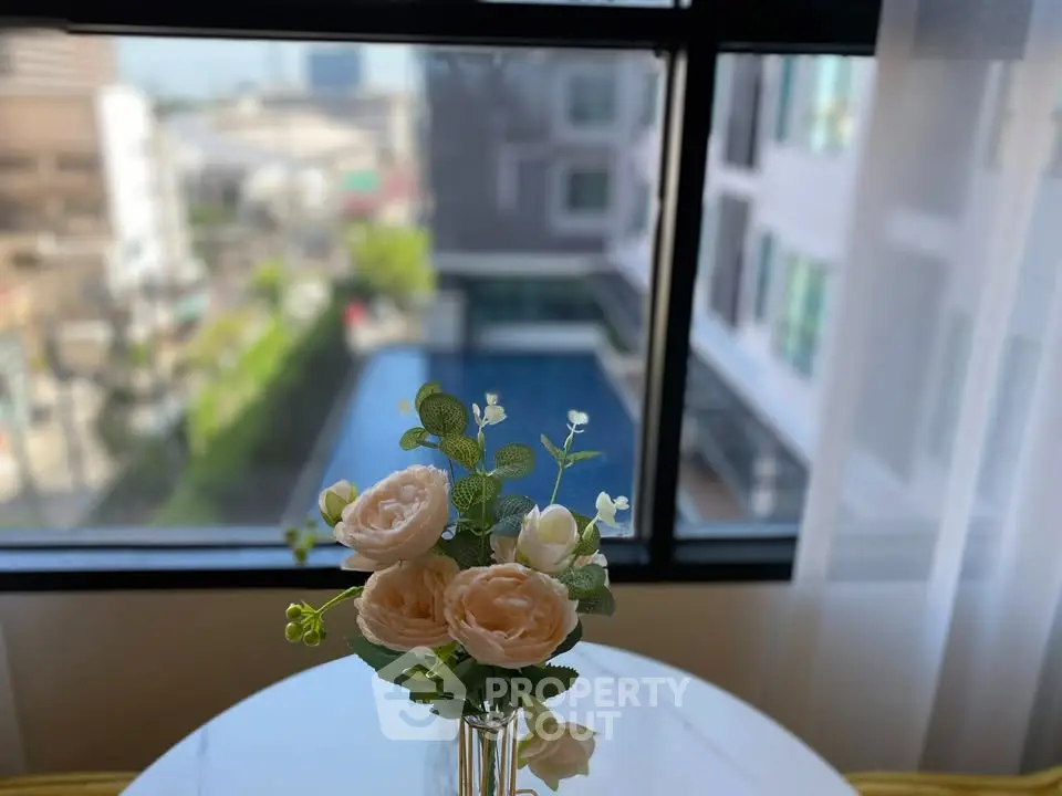 Charming interior view with elegant floral arrangement and poolside scenery through window.