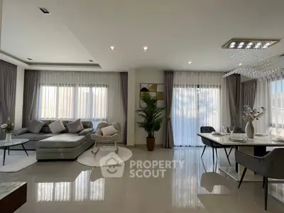 Elegant living room with modern decor and dining area, featuring large windows and luxurious furnishings.