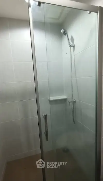 Modern shower enclosure with glass door in a sleek bathroom setting.