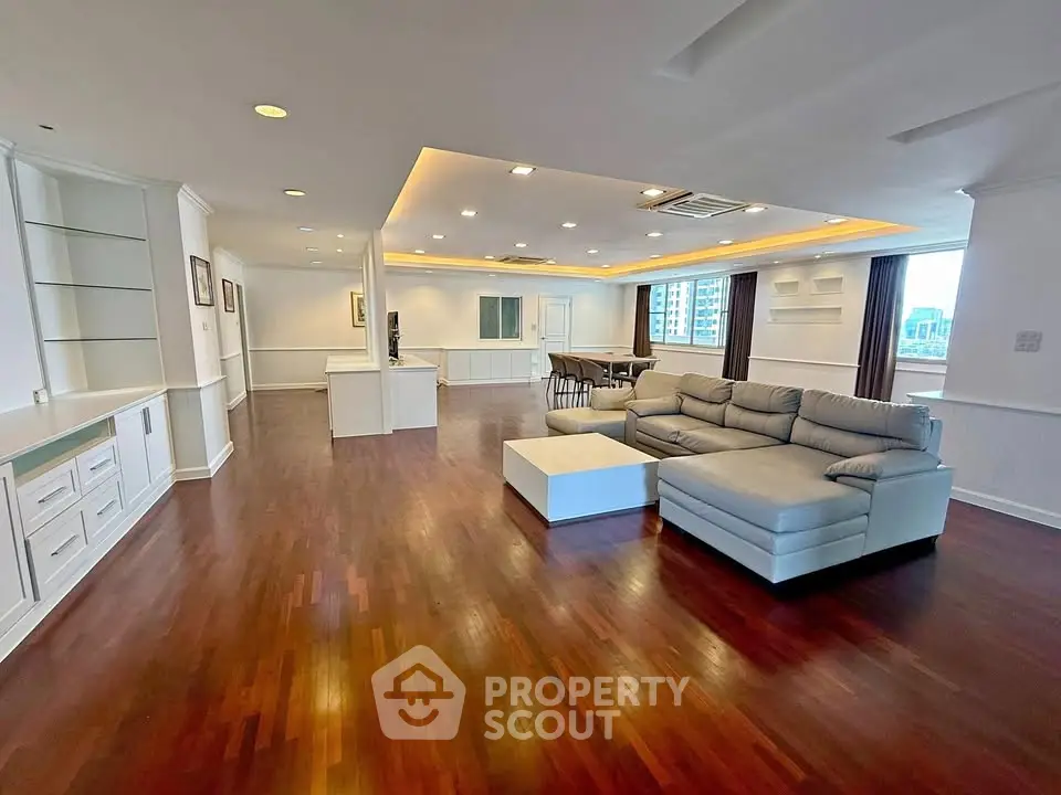 Spacious open-plan living room with elegant hardwood floors and modern furniture, ideal for luxury living.