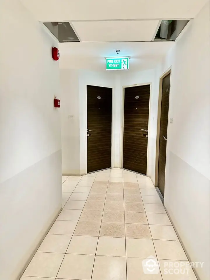 Modern apartment hallway with multiple doors and emergency exit sign