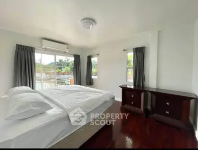 Spacious bedroom with large windows and elegant wooden flooring