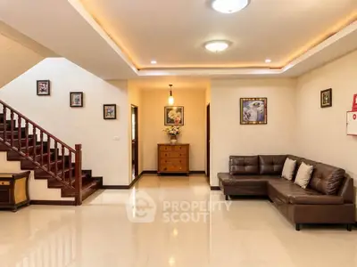 Spacious living room with elegant staircase and cozy leather sofa