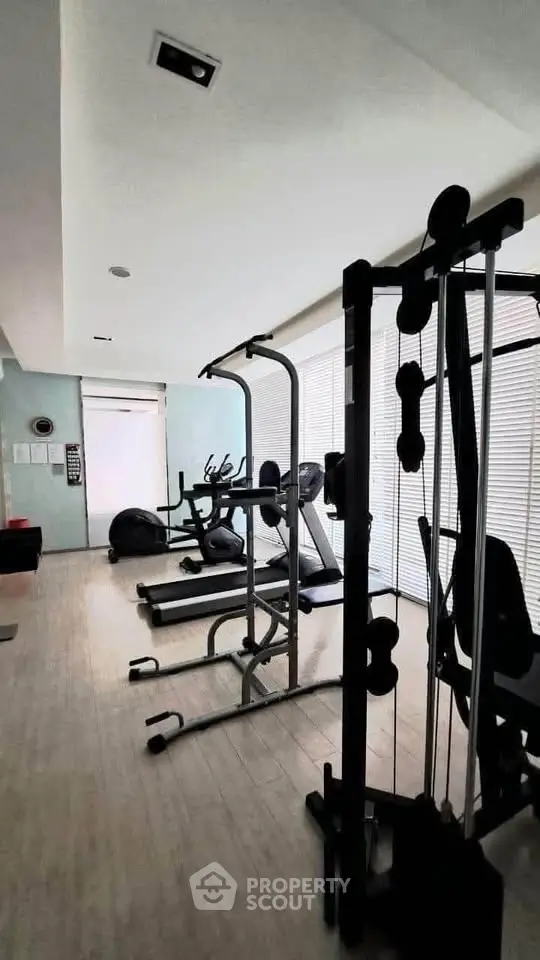 Modern gym with fitness equipment and large windows in a real estate property.