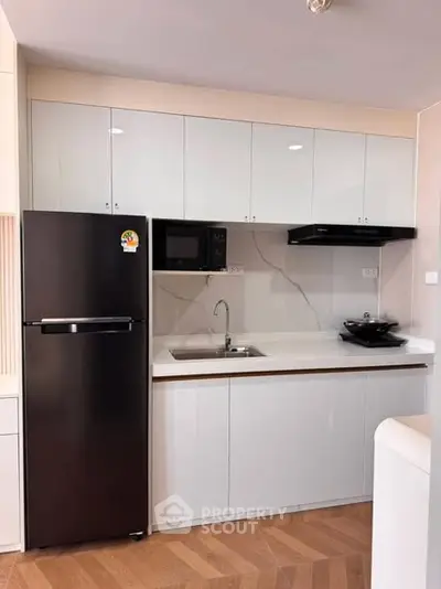 Modern kitchen with sleek cabinets, black fridge, and built-in appliances