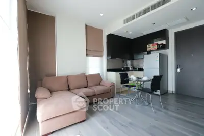 Modern living room with cozy sofa and compact kitchen in open layout apartment.
