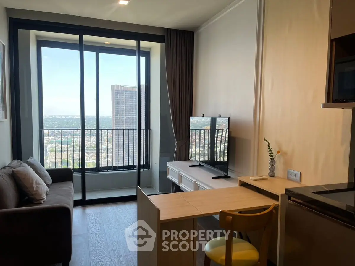 Modern living room with balcony and city view, featuring sleek furniture and natural light.