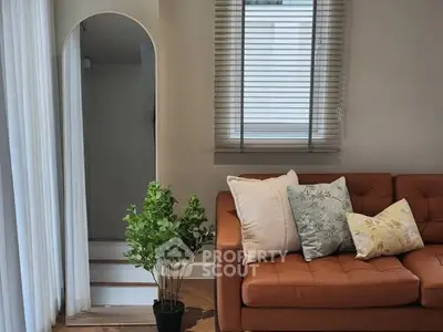 Stylish living room with modern sofa and decorative pillows, featuring a tall mirror and indoor plant.