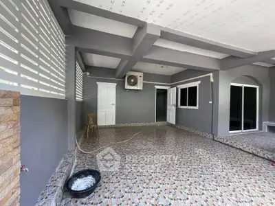 Spacious covered patio with tiled flooring and air conditioning unit, perfect for outdoor relaxation.