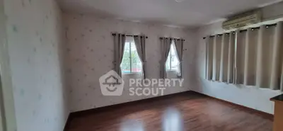 Spacious empty room with wooden flooring and large windows, perfect for customization.