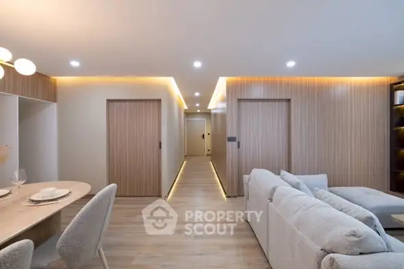 Modern living room with cozy seating and elegant dining area, featuring ambient lighting and wooden accents.