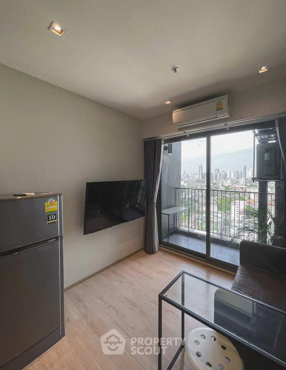 Modern living room with balcony and city view, featuring sleek furniture and air conditioning.