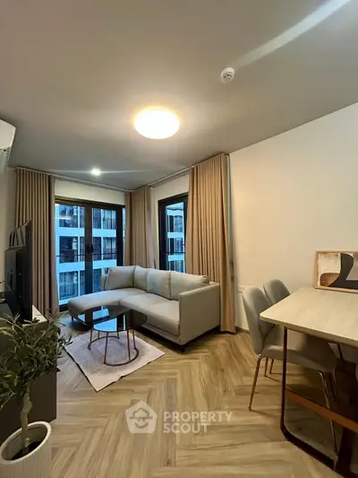 Modern living room with cozy sofa and dining area, featuring large windows and stylish decor.