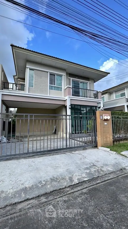 Modern two-story house with spacious driveway and gated entrance.