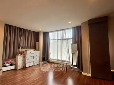 Spacious bedroom with large window and wooden flooring in modern apartment