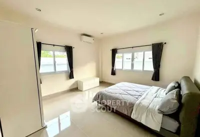 Spacious bedroom with large windows and modern furnishings in a bright, airy setting.