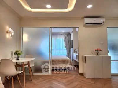 Modern apartment interior with stylish dining area and cozy bedroom separated by frosted glass sliding doors.