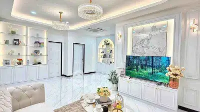Luxurious living room with elegant lighting and modern decor, featuring a large TV and stylish shelving.