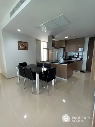 Modern kitchen with sleek cabinetry and stainless steel appliances seamlessly transitions to a cozy dining area, perfect for entertaining.