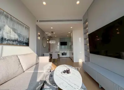 Modern living room with open kitchen, featuring sleek furniture and contemporary decor.