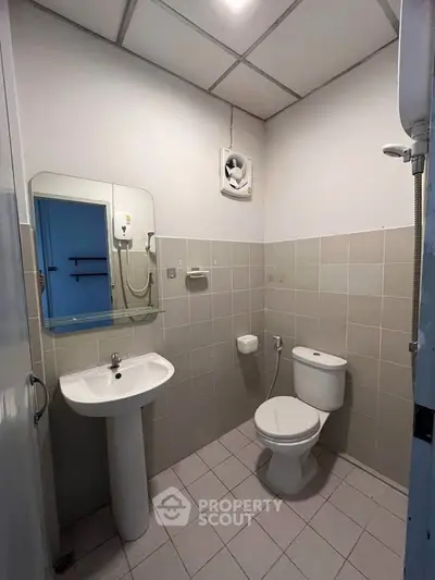 Compact bathroom with pedestal sink and toilet in neutral tones.