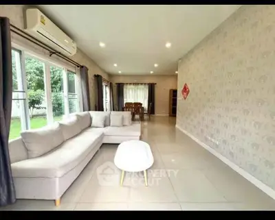 Spacious living room with modern decor and large windows overlooking a garden, perfect for family gatherings.