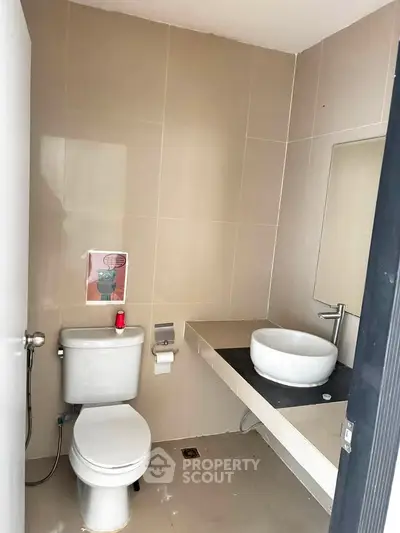 Modern bathroom with sleek fixtures and minimalist design, featuring a stylish vessel sink and contemporary toilet.