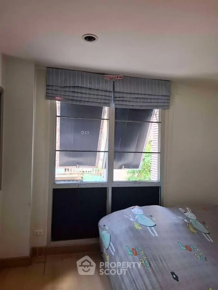 Cozy bedroom with charming window view and playful bedding in a modern apartment.