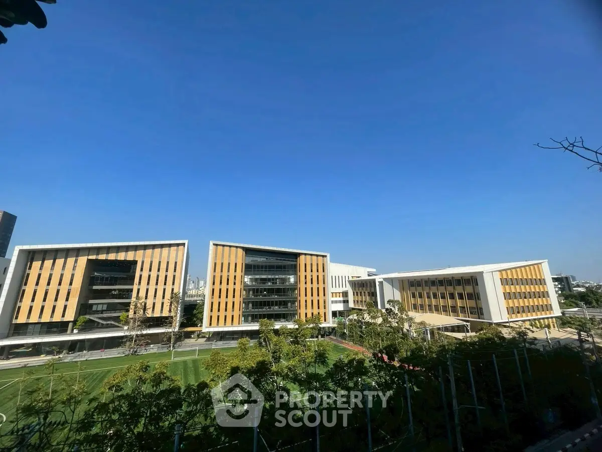 Modern architectural building with expansive green lawn under clear blue sky.