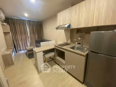 Modern open-layout kitchen with sleek appliances and cozy living area in stylish apartment.