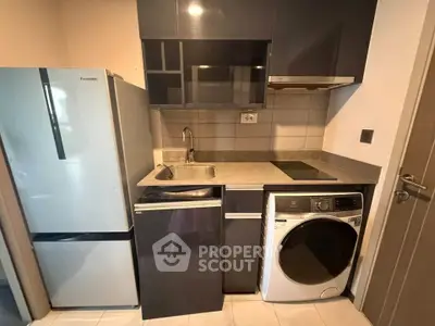 Compact modern kitchen with appliances including fridge, washing machine, and electric stove.