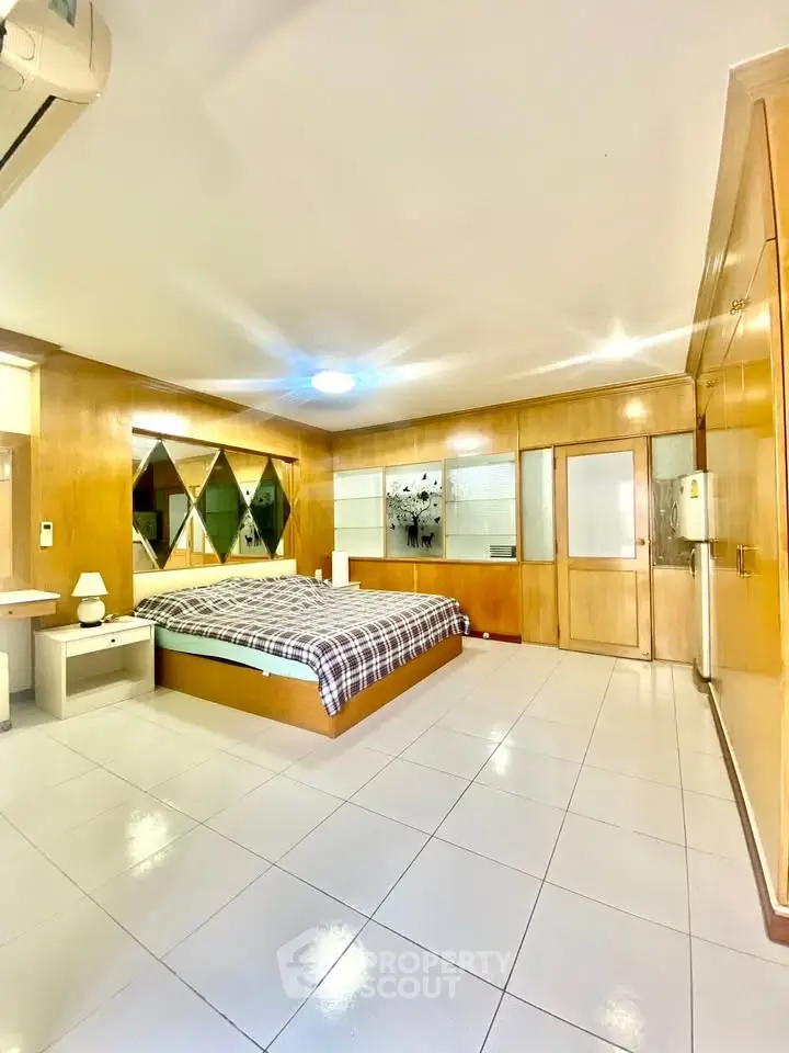 Spacious bedroom with modern design and ample natural light, featuring elegant wood paneling and stylish decor.