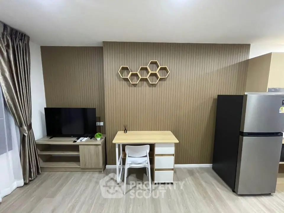 Modern living room with stylish decor, TV unit, and sleek refrigerator in a cozy apartment.