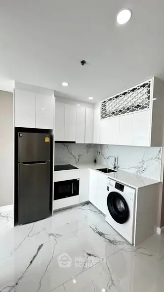 Modern kitchen with sleek white cabinets, marble flooring, and built-in appliances including fridge and washing machine.