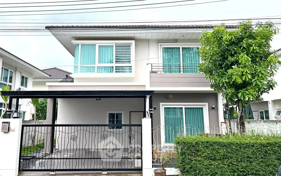 Modern two-story house with gated driveway and lush greenery