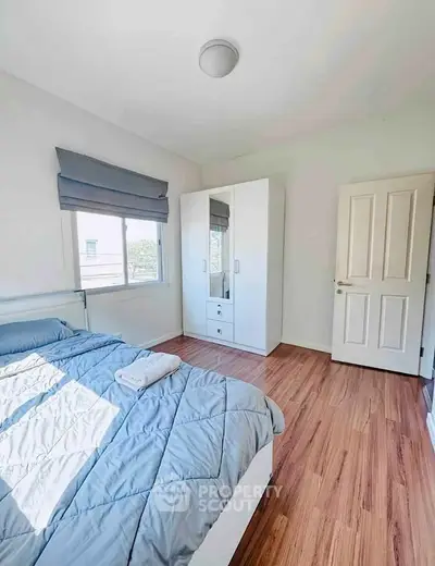 Bright bedroom with wooden flooring and modern wardrobe