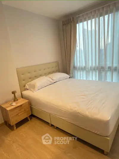 Cozy bedroom with large window and modern furnishings in a bright apartment.