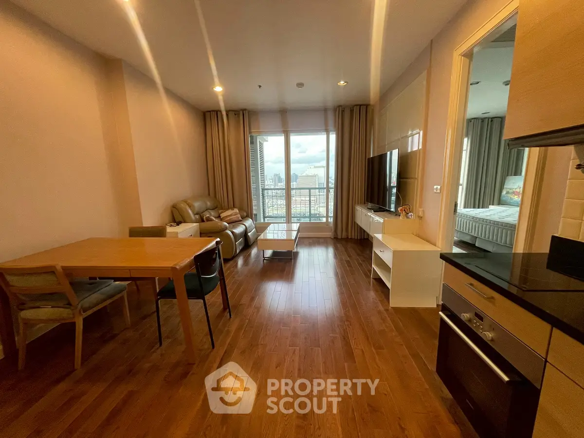 Spacious living room with wooden flooring and city view, featuring modern furniture and open layout.