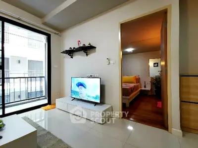 Modern living room with TV and view into cozy bedroom