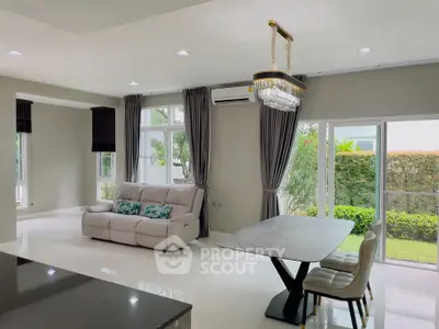 Spacious modern living room with elegant chandelier and garden view, perfect for family gatherings.