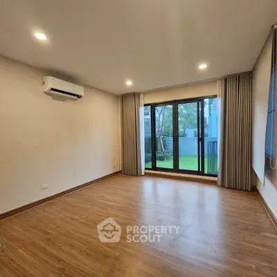 Spacious living room with wooden flooring and large window overlooking garden.