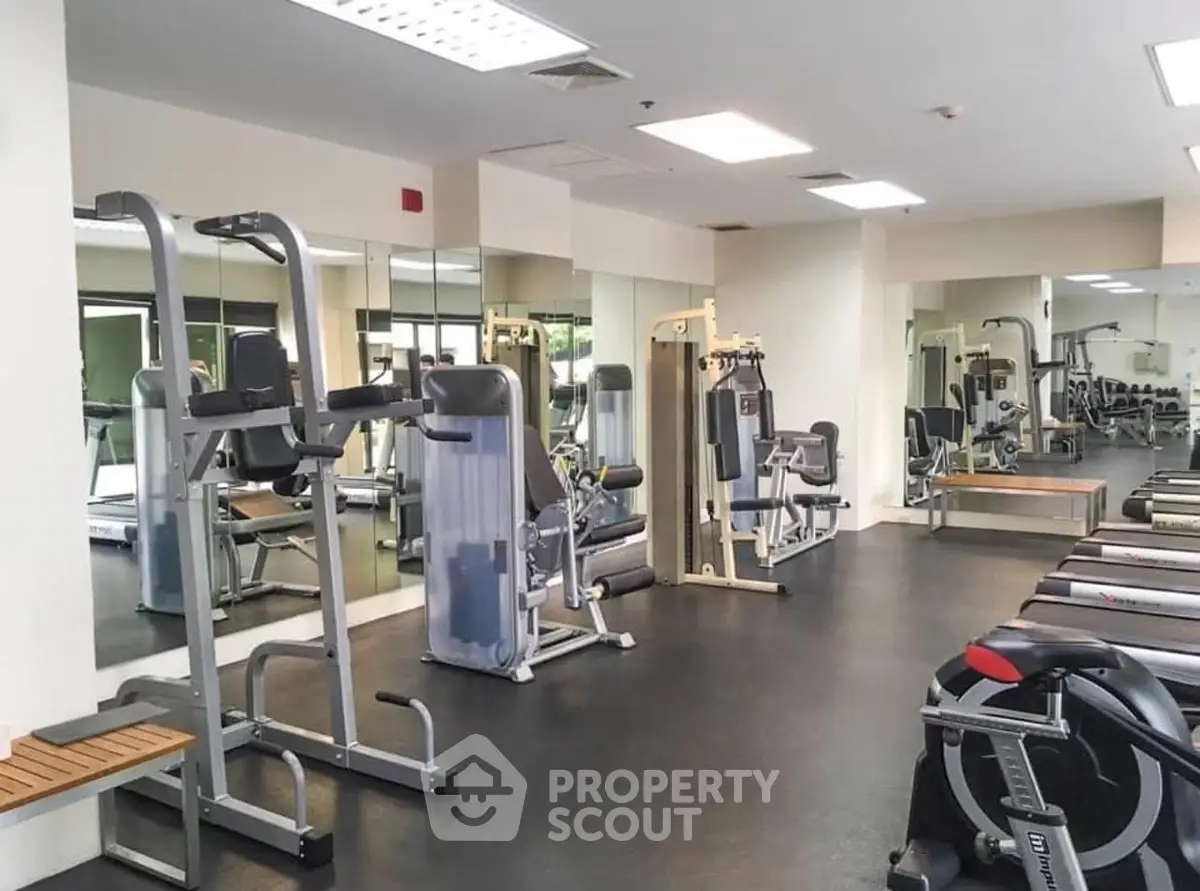 Spacious modern gym with state-of-the-art fitness equipment and mirrored walls in a luxury building.