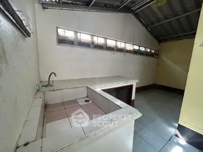 Spacious kitchen with tiled countertops and unique window design, perfect for renovation.