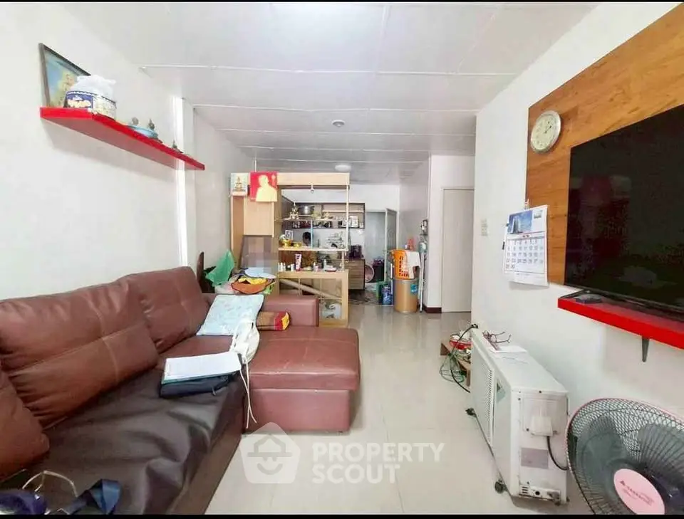Cozy living room with brown leather sofa and wall-mounted TV, ideal for relaxation.