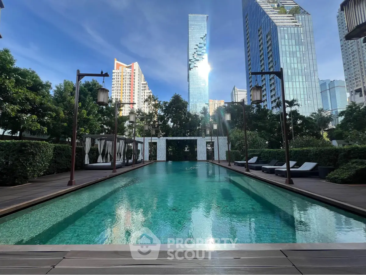Luxurious outdoor pool with city skyline view and lush greenery, perfect for relaxation and leisure.