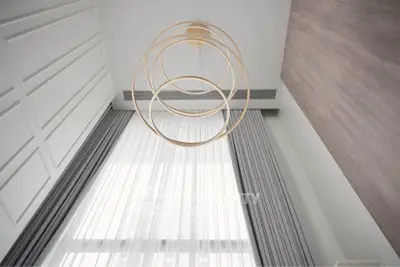 Elegant modern interior with high ceiling and stylish chandelier in a luxurious living space.