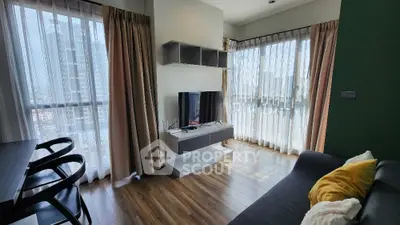 Modern living room with large windows and stylish decor in a high-rise apartment.